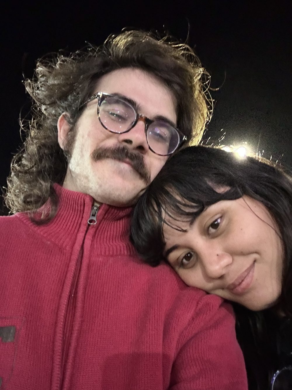 Pedro em um abraço com sua companheira, à noite